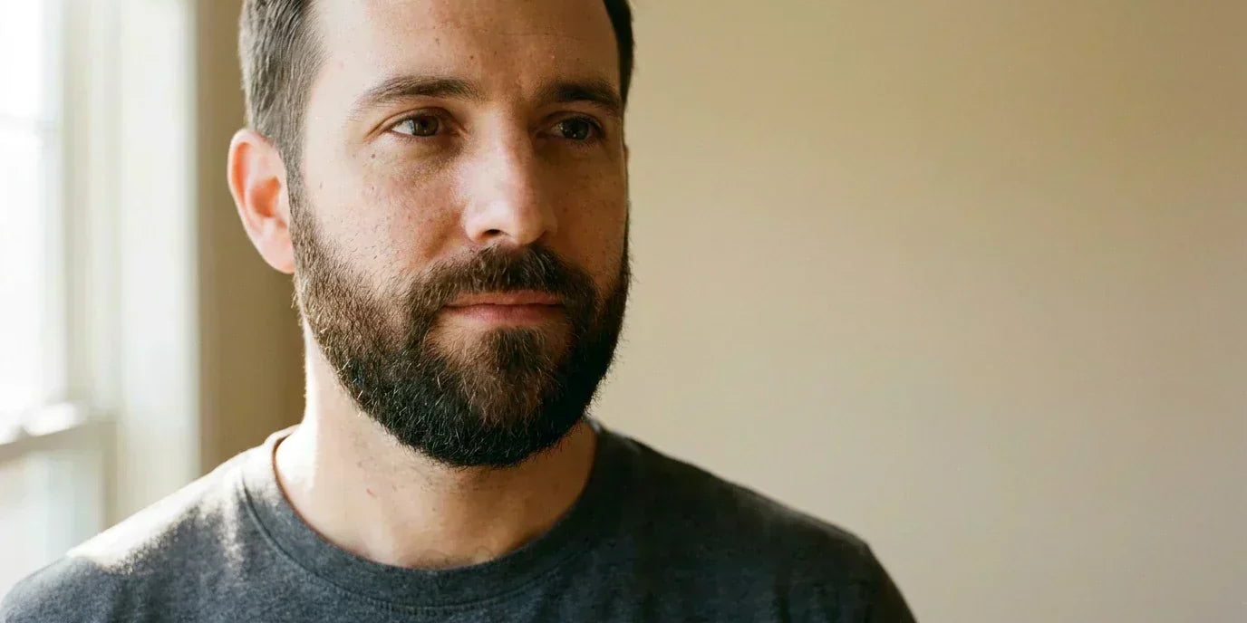 Man in his mid-30s with a healthy, well-groomed beard, illustrating a successful assisted beard growth journey