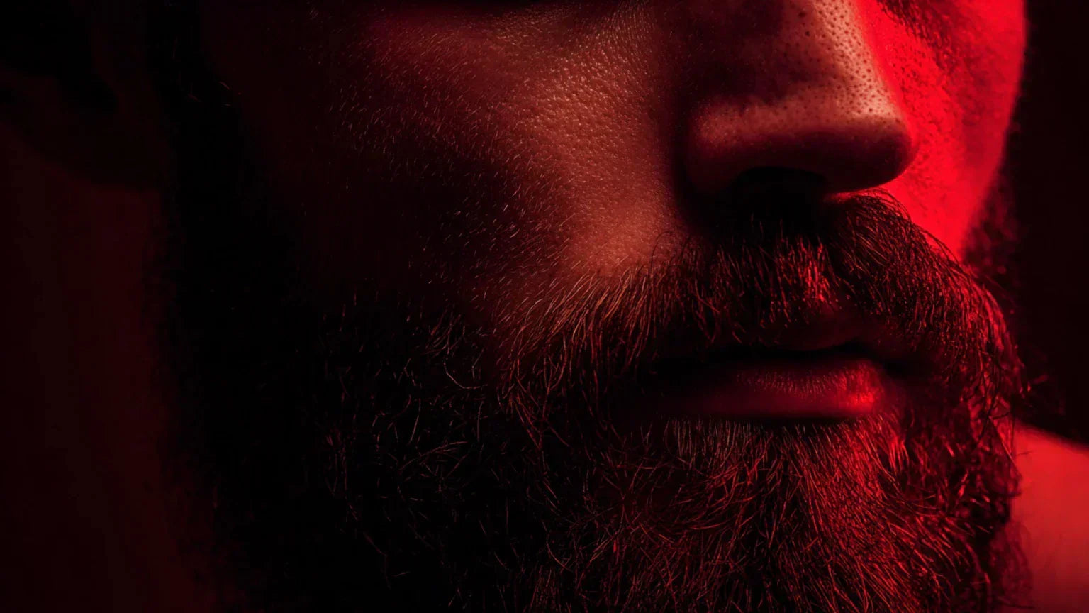 Close-up of a man's beard and jawline illuminated by red light therapy