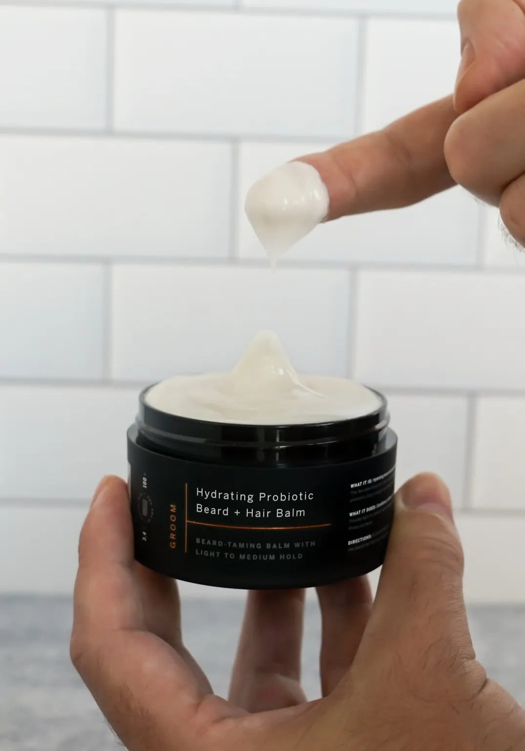 Close-up of Stubble & Stache Groom Beard + Hair Balm being scooped with a finger, showing its smooth, butter-like texture that applies easily without stiffness.