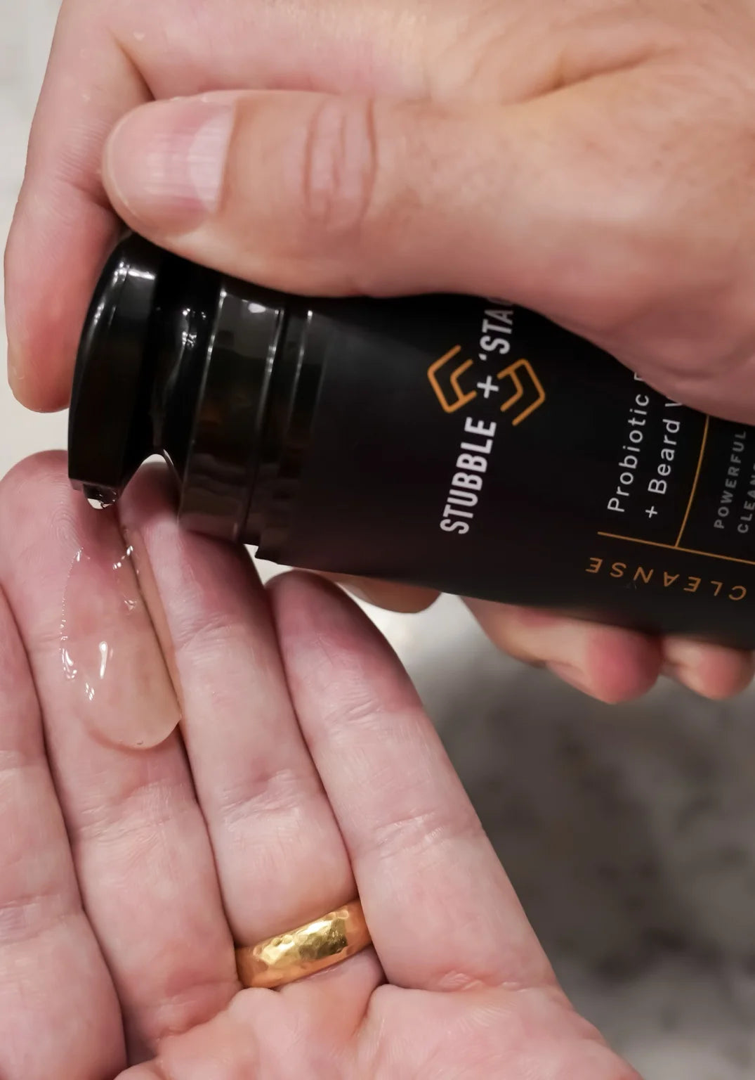 Hand pumping Stubble & Stache Cleanse — daily probiotic face and beard wash — into palm