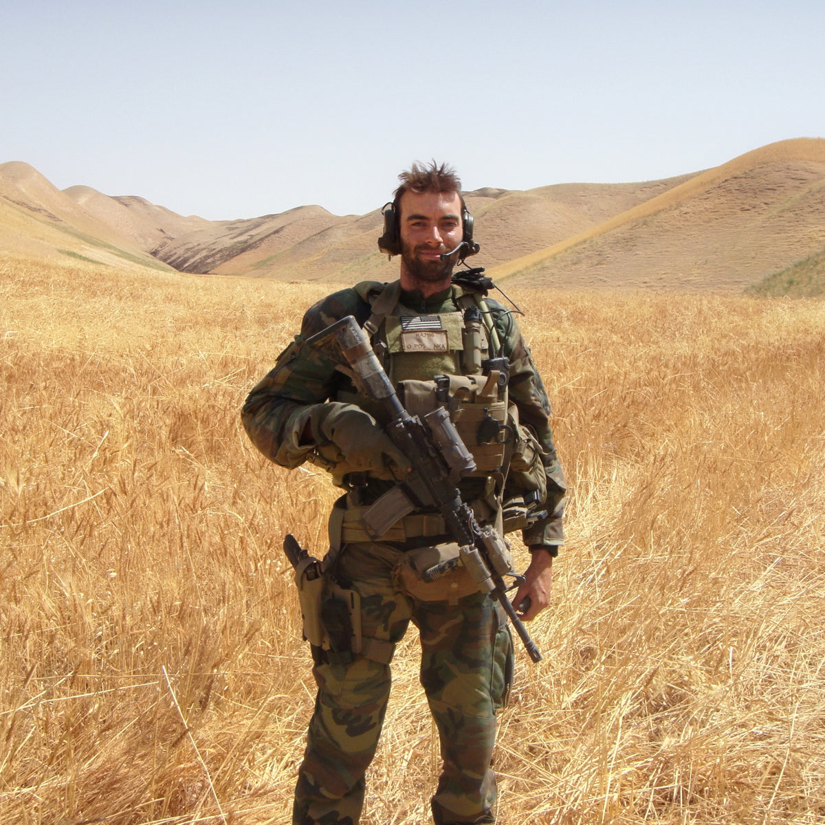 Nick Karnaze, founder of stubble + 'stache, on deployment in Afghanistan, standing in a wheat field in full gear