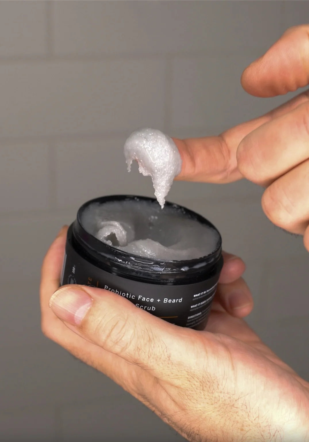 Man scooping Stubble & Stache Exfoliate Probiotic Face + Beard Scrub with finger, showing texture and consistency